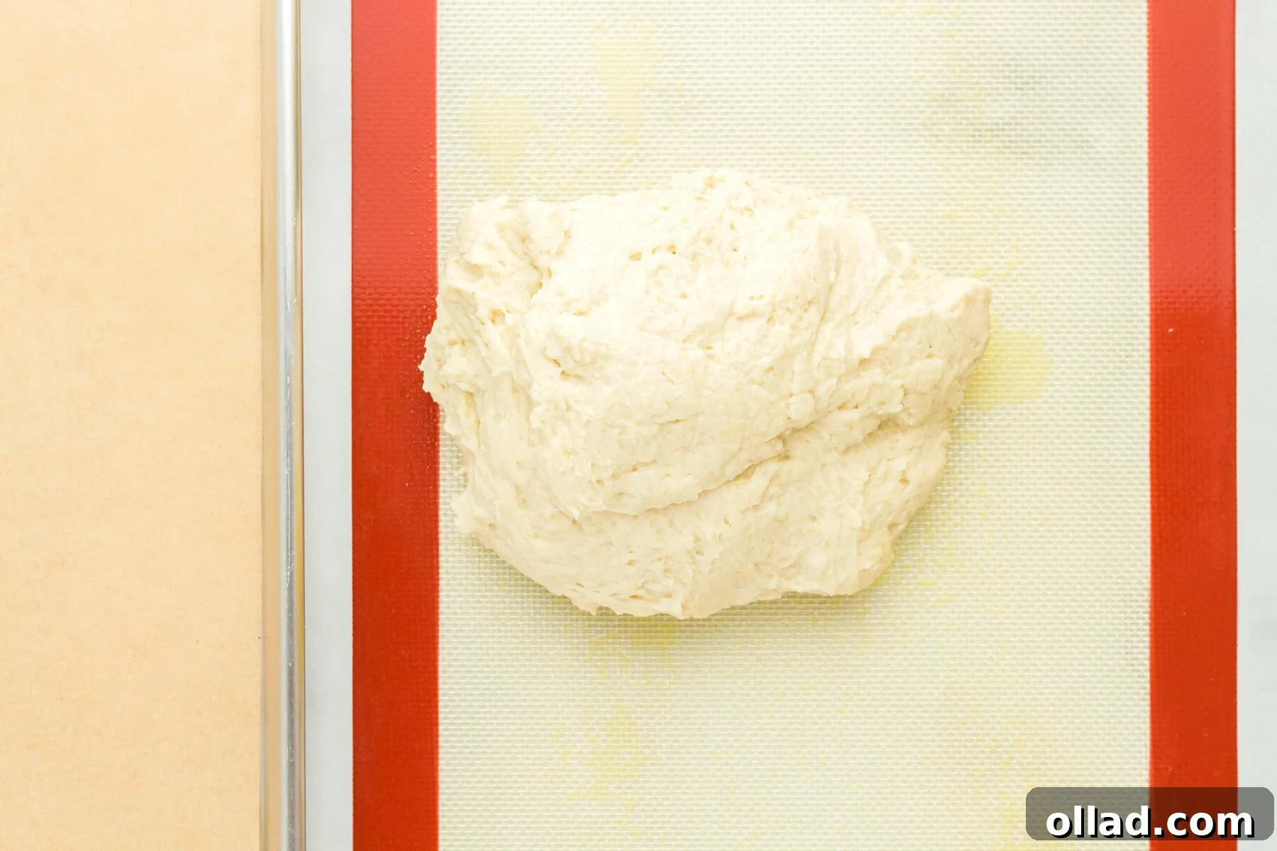 A smooth, round ball of gluten-free hot dog bun dough on a clean surface.