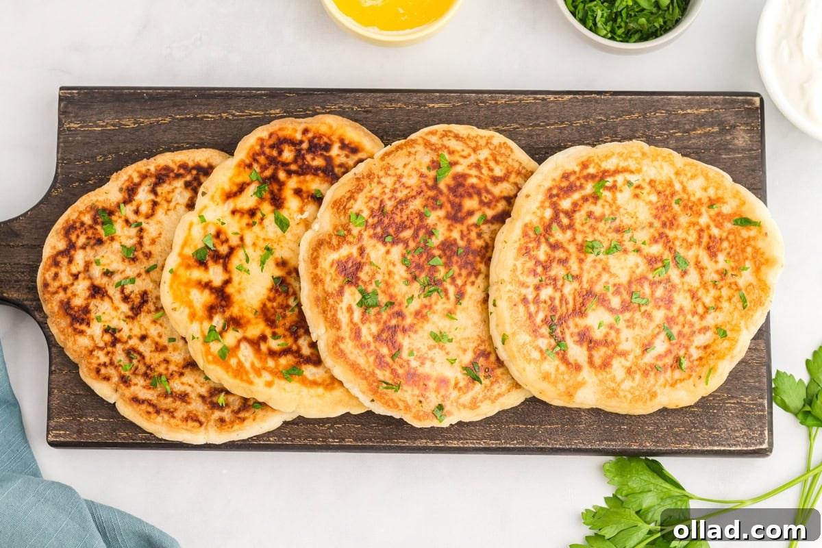Pillowy Gluten-Free Flatbread 10 four gluten-free flatbread laying on a black serving platter topped with fresh chopped parsley