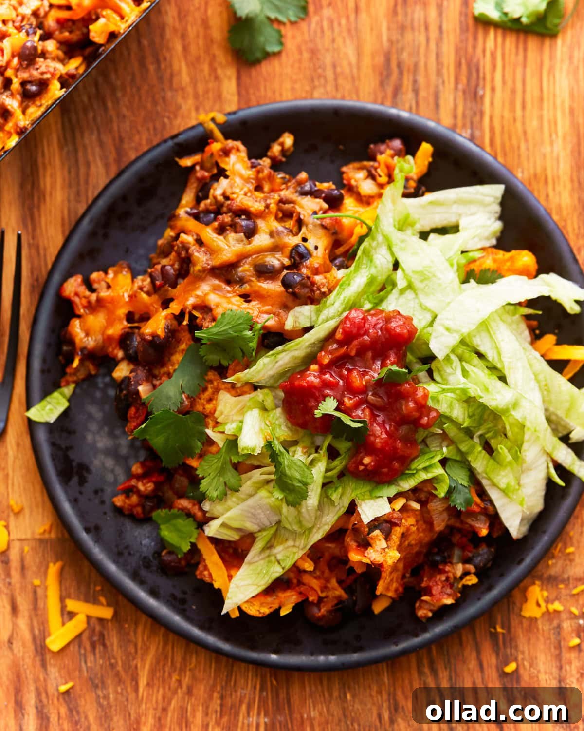 a serving of walking taco casserole on a plate with lettuce and salsa.