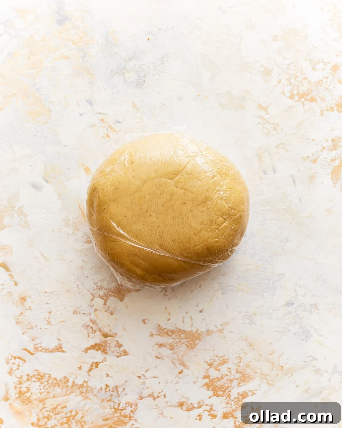 A ball of gluten-free pasta dough wrapped in plastic wrap.