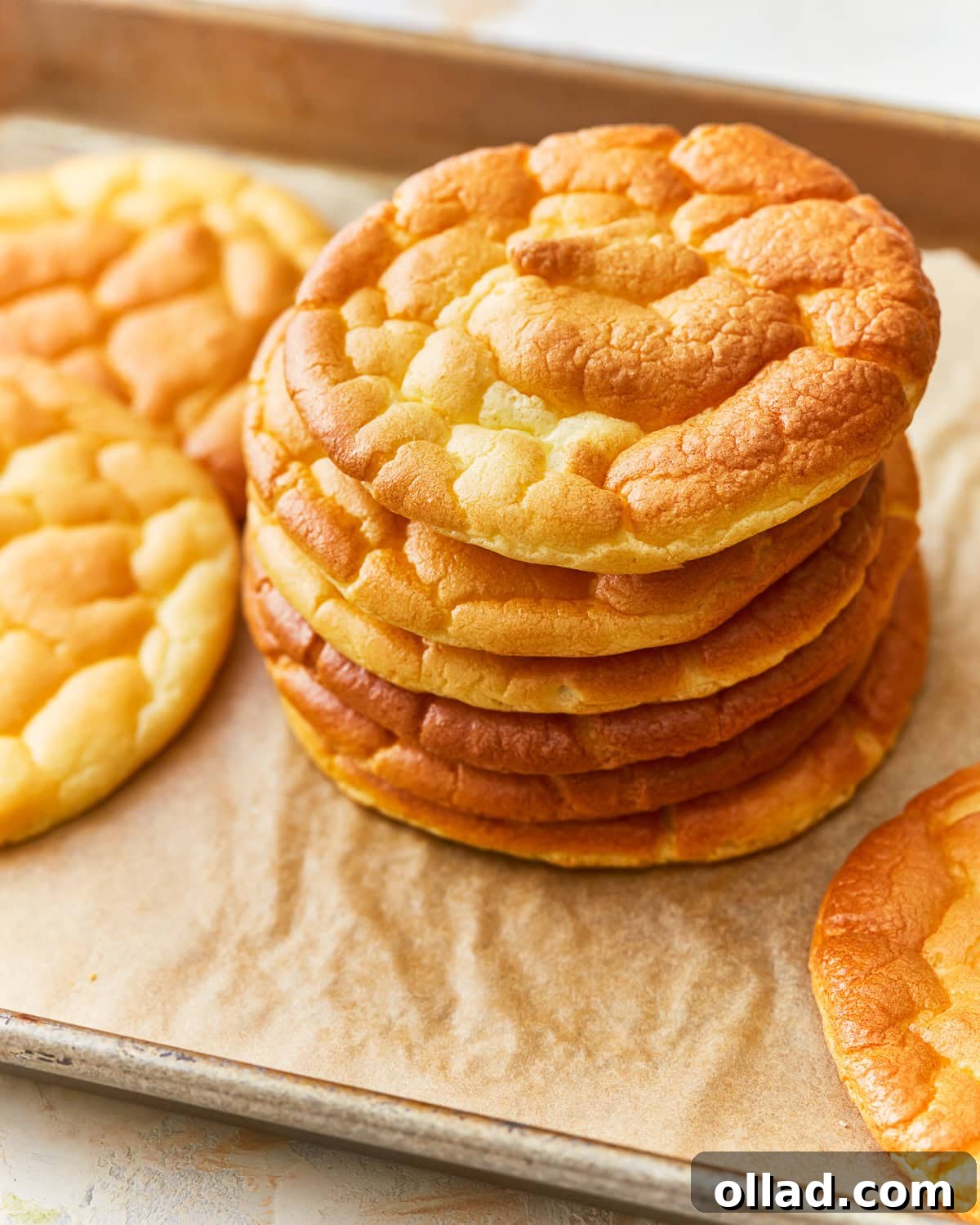 A stack of cloud bread rounds on a parchment lined baking sheet, ready to be served.
