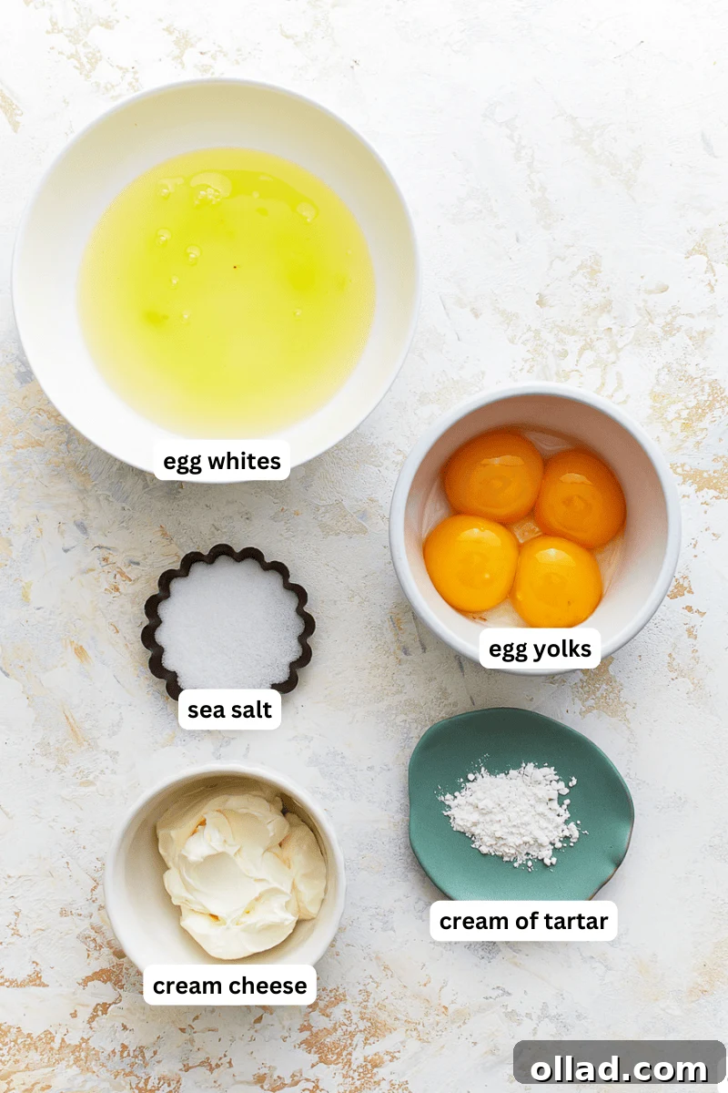 Various ingredients for cloud bread laid out on a clean surface: eggs, cream of tartar, cream cheese, and sea salt.
