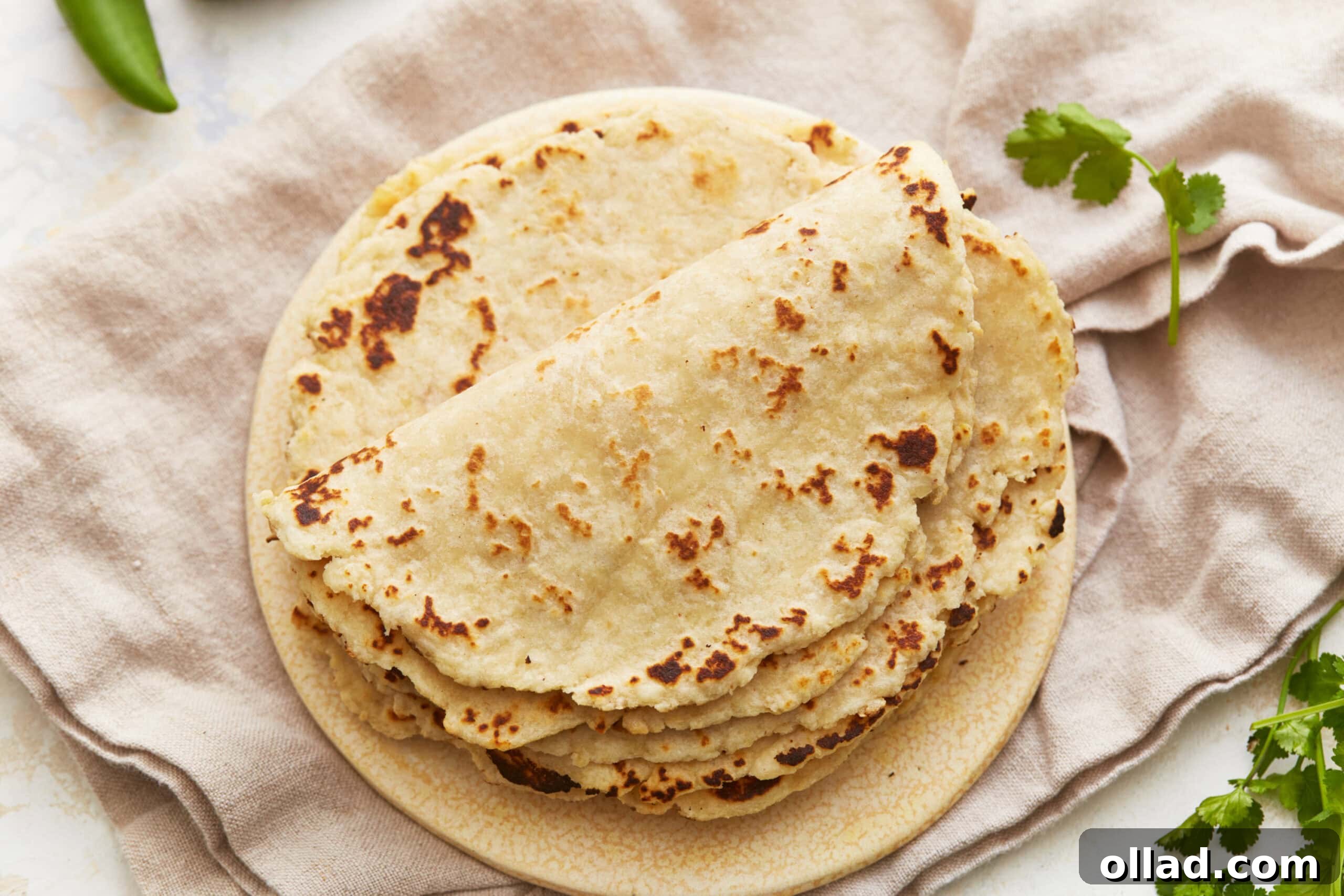 Overhead view of a stack of fluffy almond flour tortillas on a simple white plate, arranged invitingly for a healthy meal.