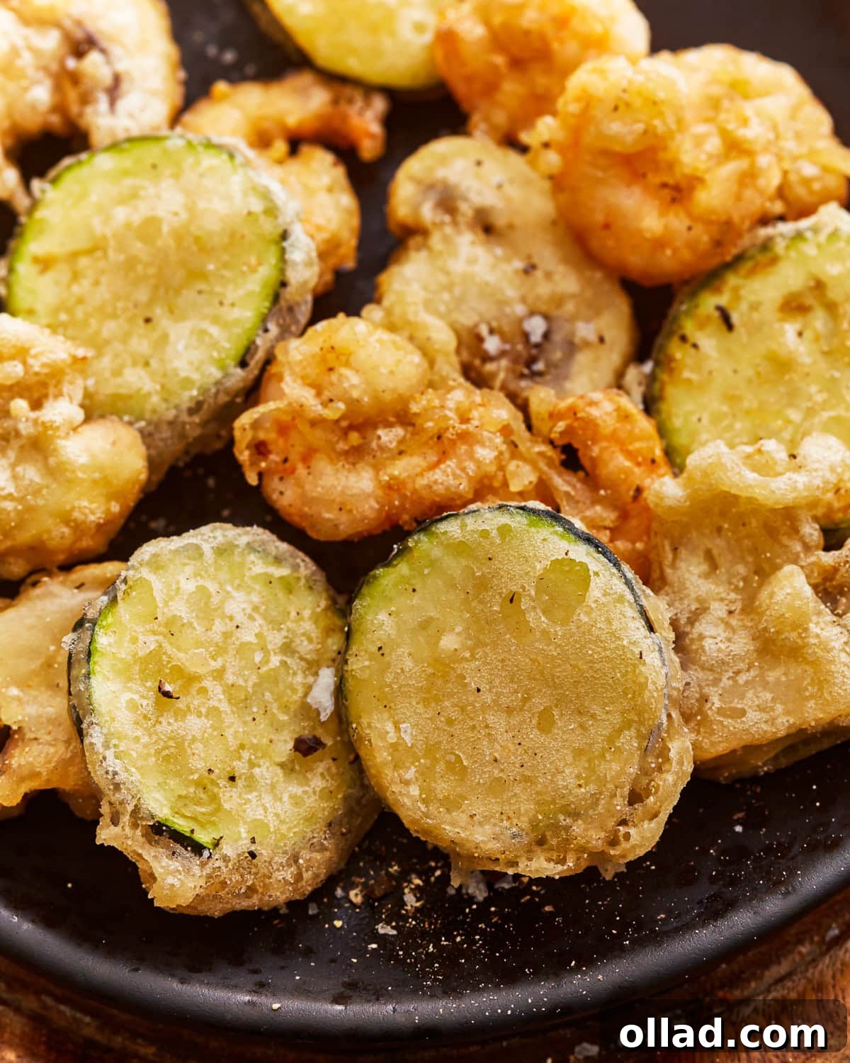 A beautifully arranged plate of golden, crispy gluten-free tempura with various vegetables and shrimp.