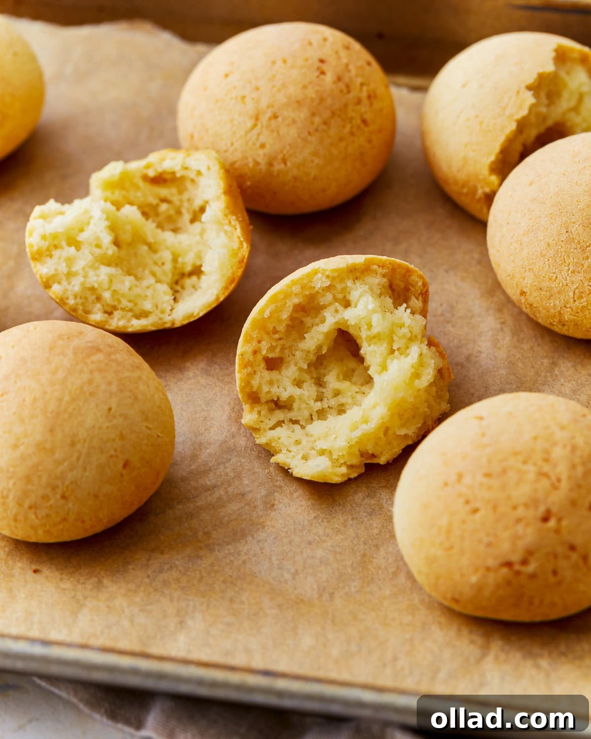 Freshly baked Pandebono, Colombian cheese bread, arranged on a parchment-lined baking sheet, golden brown and ready to eat.