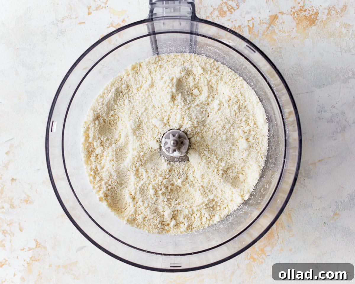 Dry ingredients for pandebono, feta cheese, masa harina, and tapioca flour, in a food processor, ready to be pulsed.