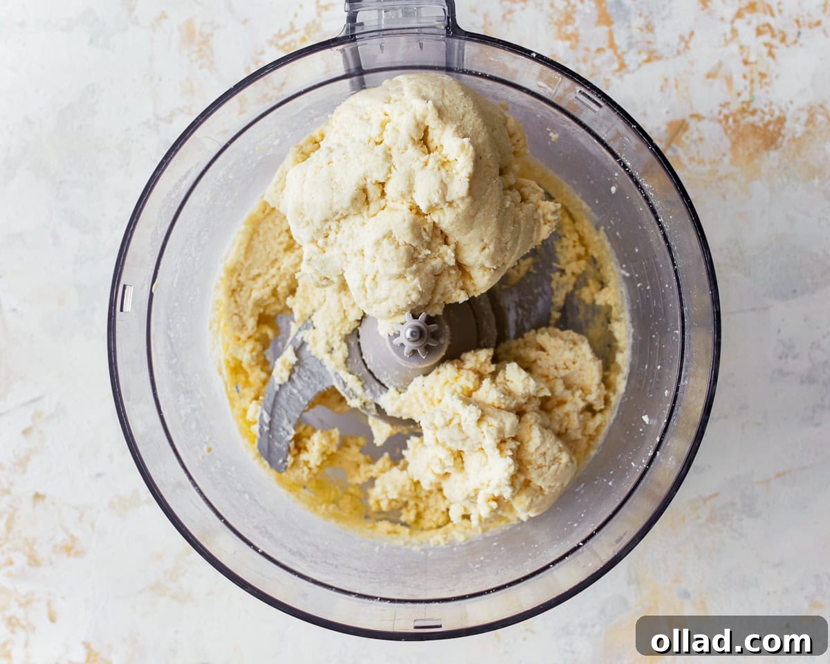 Wet ingredients, an egg and melted butter, added to the dry pandebono mixture in a food processor.