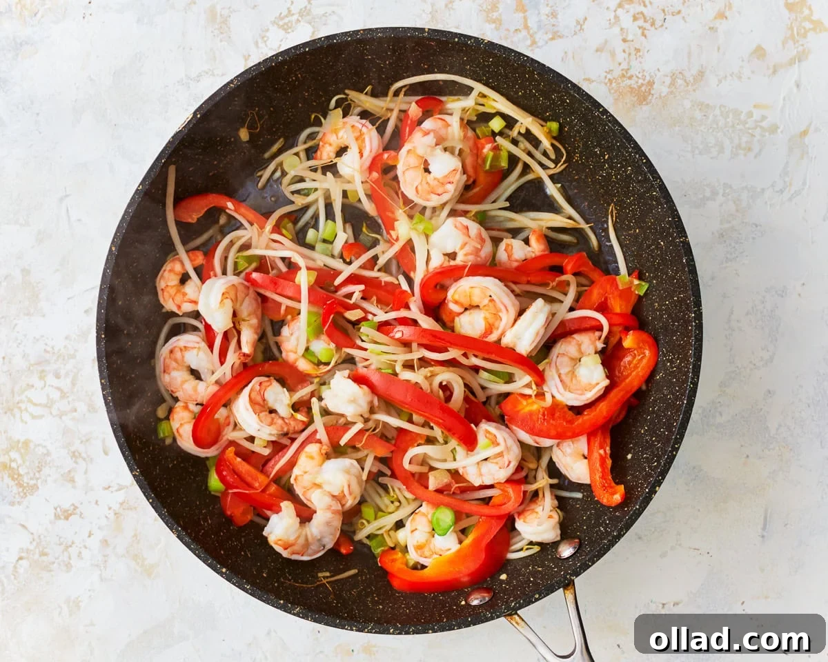 Shrimp and vegetables for gluten-free pad thai in a skillet