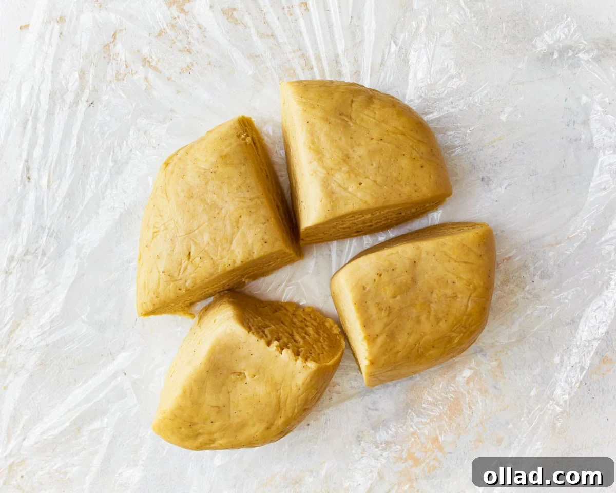 A ball of rested gluten-free egg noodle dough divided into four manageable portions, ready for rolling.