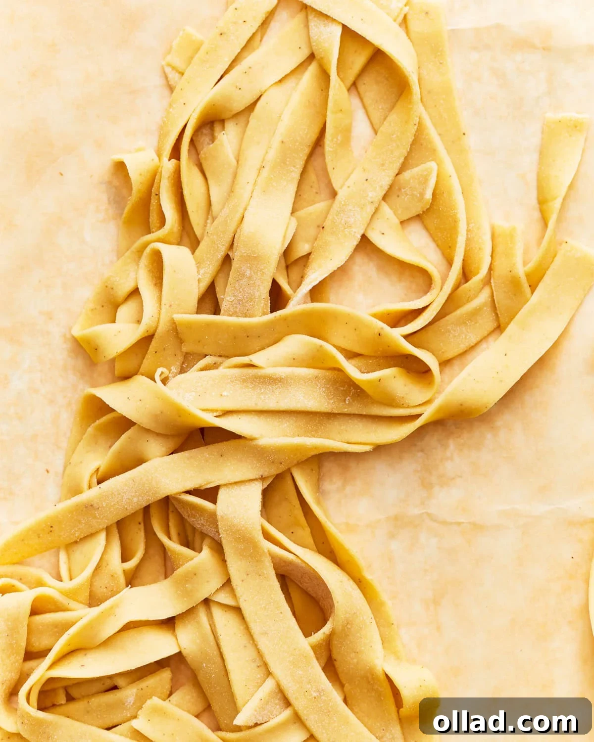 Freshly cut gluten-free egg noodles carefully laid out on parchment paper, ready for cooking or freezing.