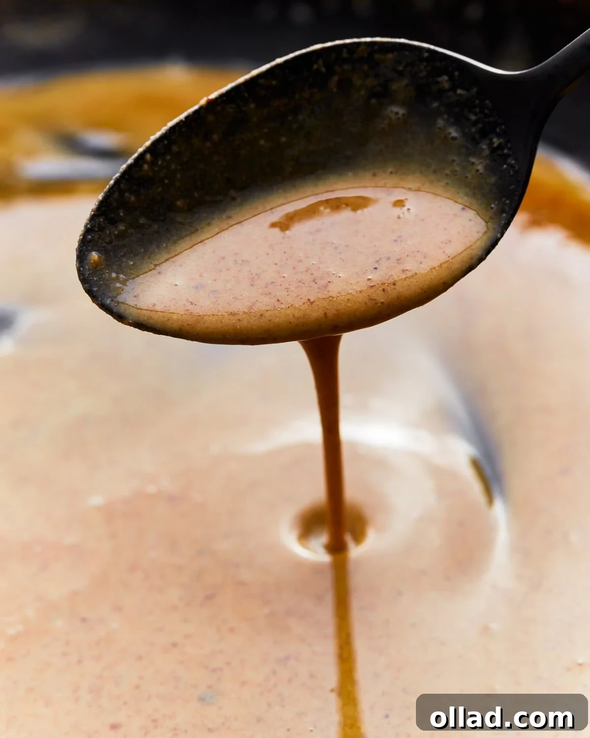 Close up of a spoon scooping gluten-free roux from a skillet.