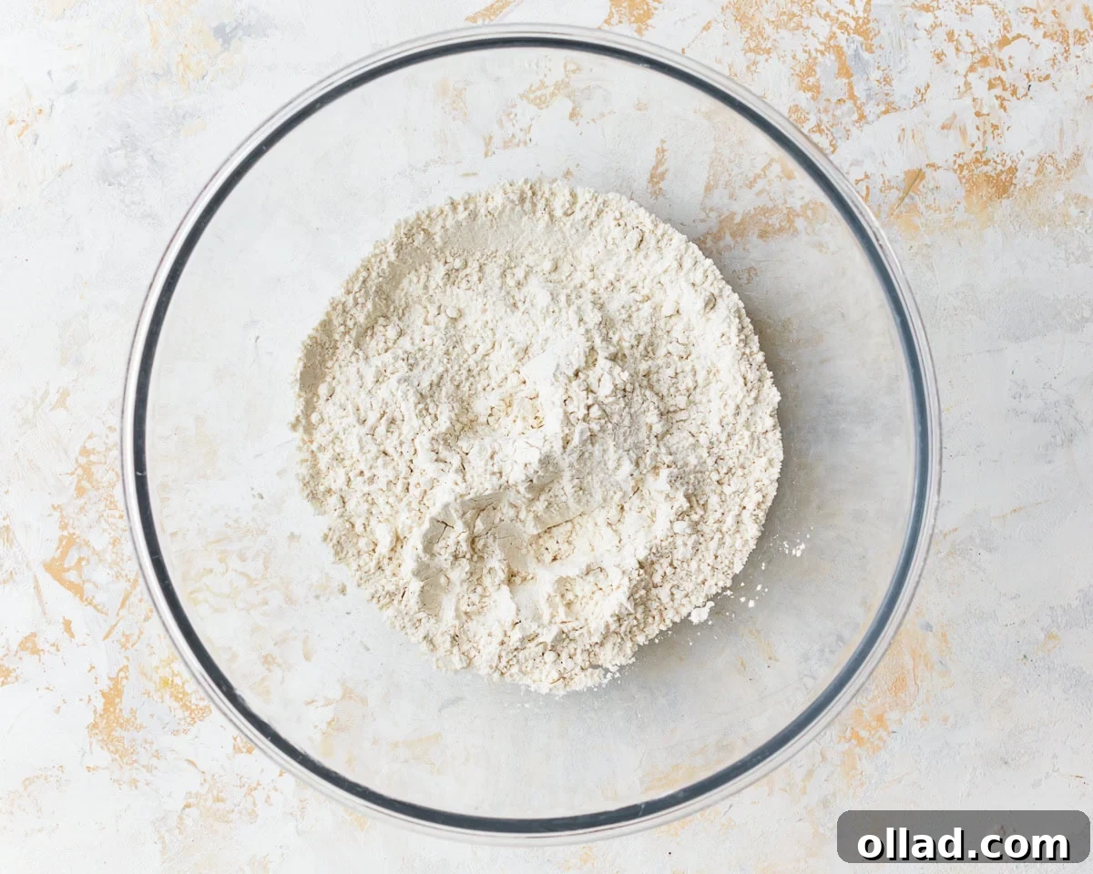 Unbelievably Flaky Gluten-Free Puff Pastry 5 Dry ingredients for gluten-free puff pastry, including flour, xanthan gum, sugar, and salt, mixed in a glass bowl.