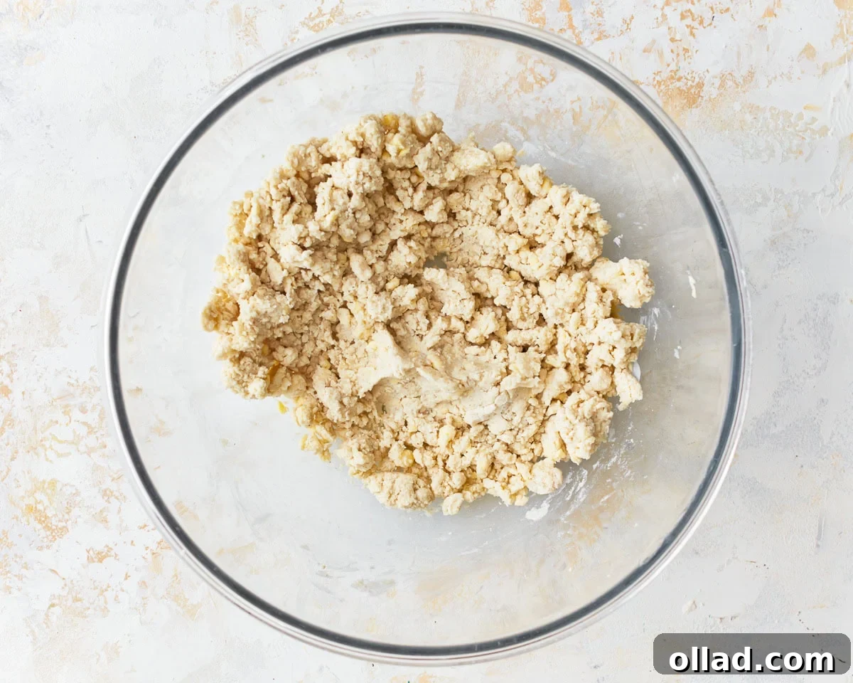Unbelievably Flaky Gluten-Free Puff Pastry 7 A loose, shaggy dough beginning to form in a glass mixing bowl after adding cold water.