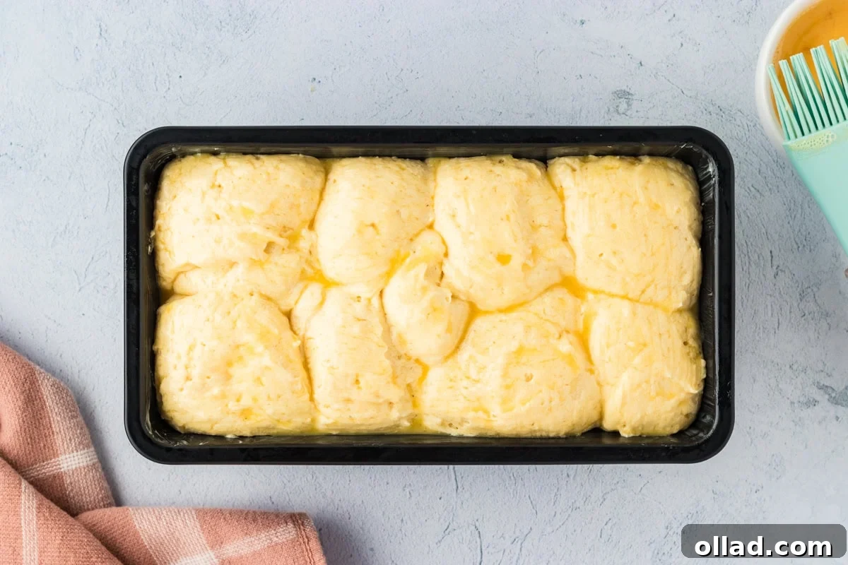 Fluffy Gluten-Free Brioche 15 Gluten-free brioche dough brushed with egg wash in a loaf pan.