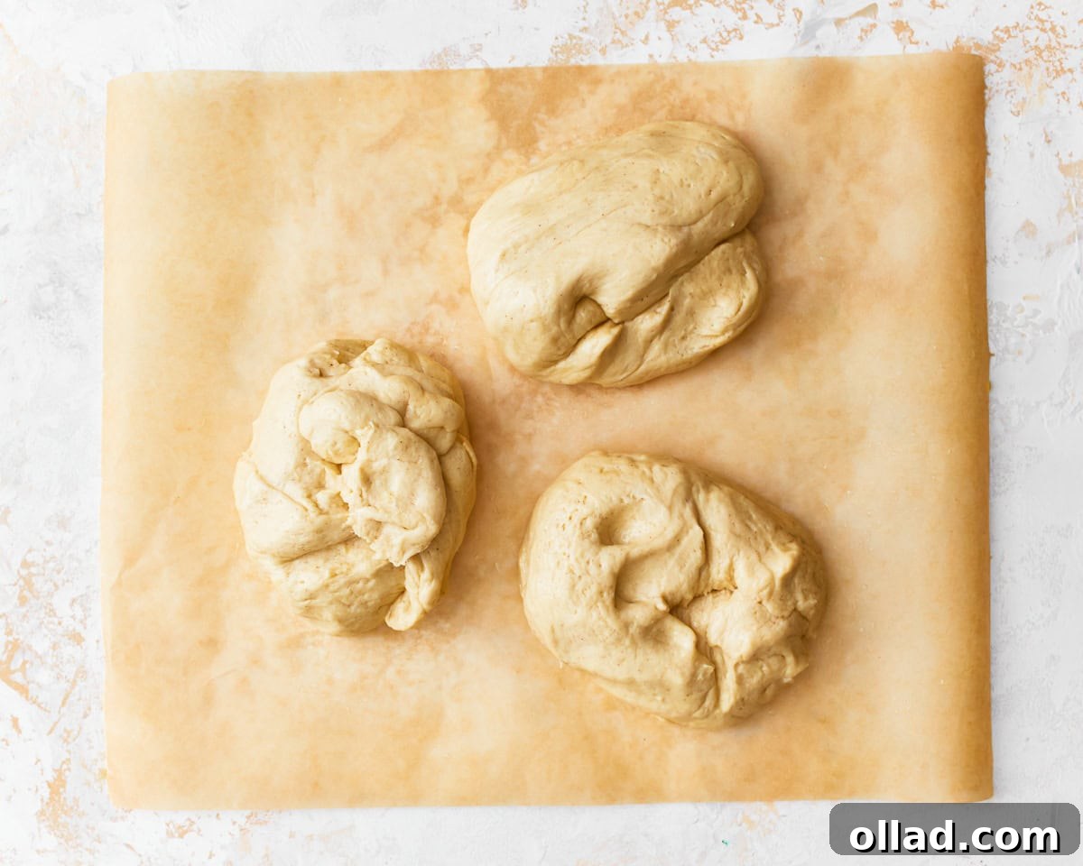 Gluten-free challah bread divided into three portions on a piece of parchment paper.
