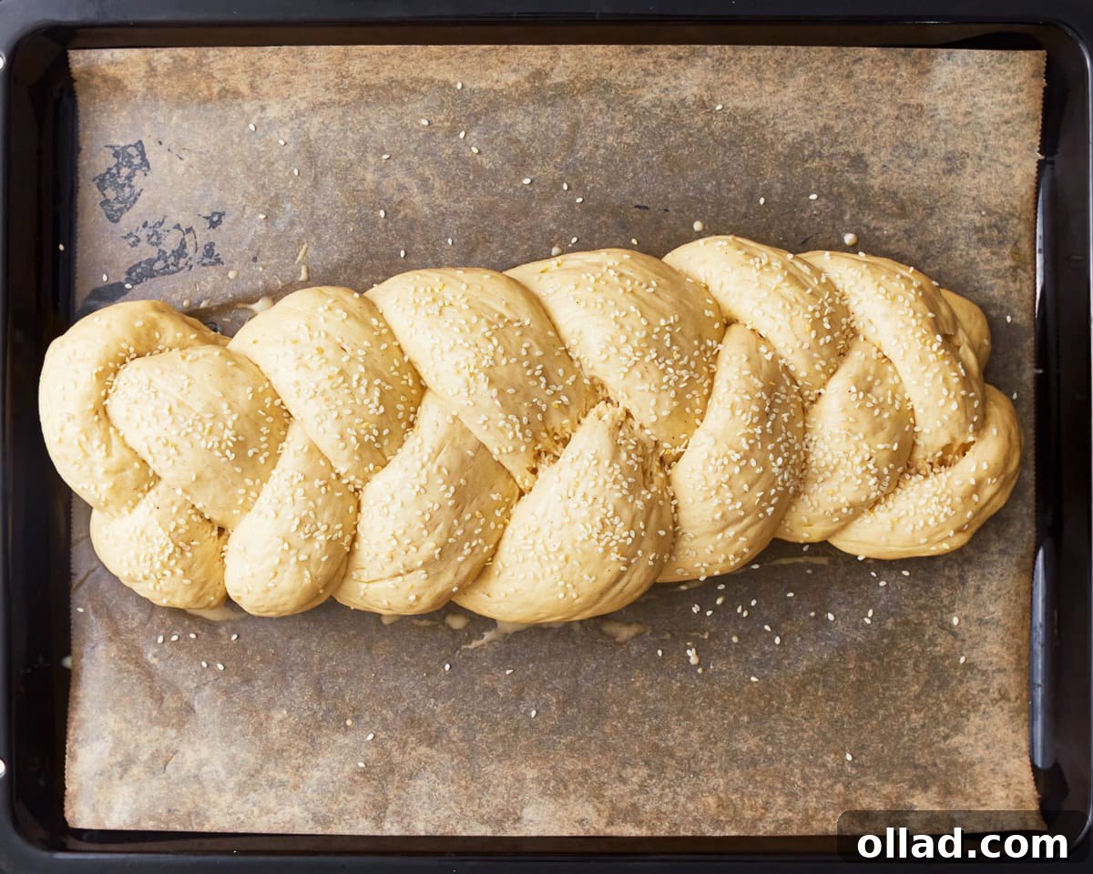 Gluten-free challah bread dough shaped into a braided loaf and topped with sesame seeds.
