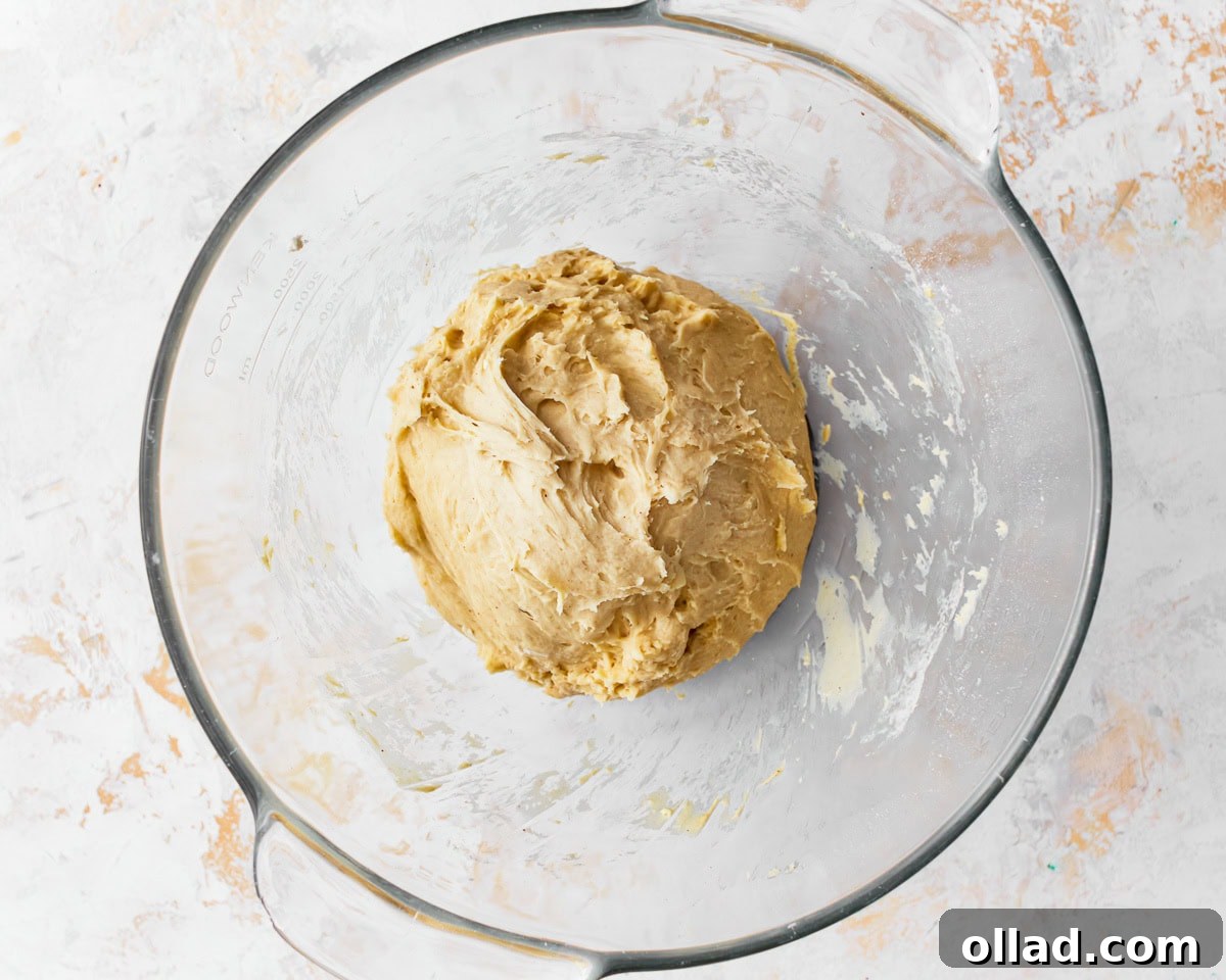 A sticky dough for gluten-free challah bread in a glass mixing bowl.