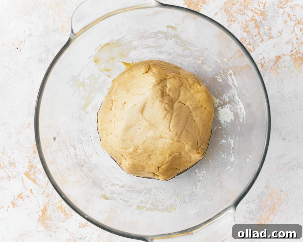 The dough for gluten-free challah bread after the first proof in a glass mixing bowl.