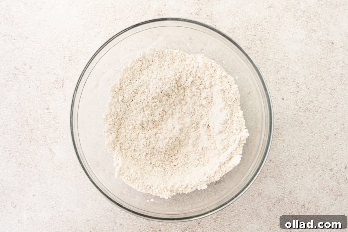 Dry ingredients for gluten-free popovers (flour, salt, xanthan gum) in a glass mixing bowl.