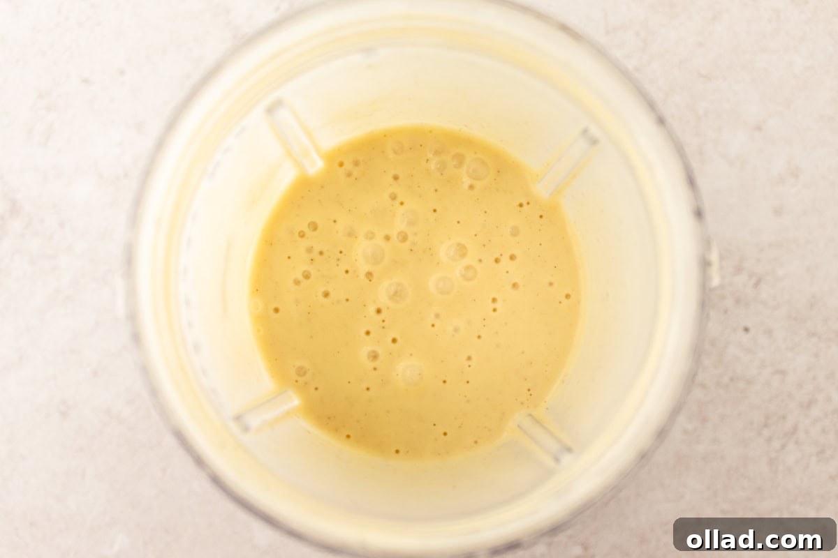 Wet ingredients for gluten-free popovers (eggs, milk, melted butter) in a blender.