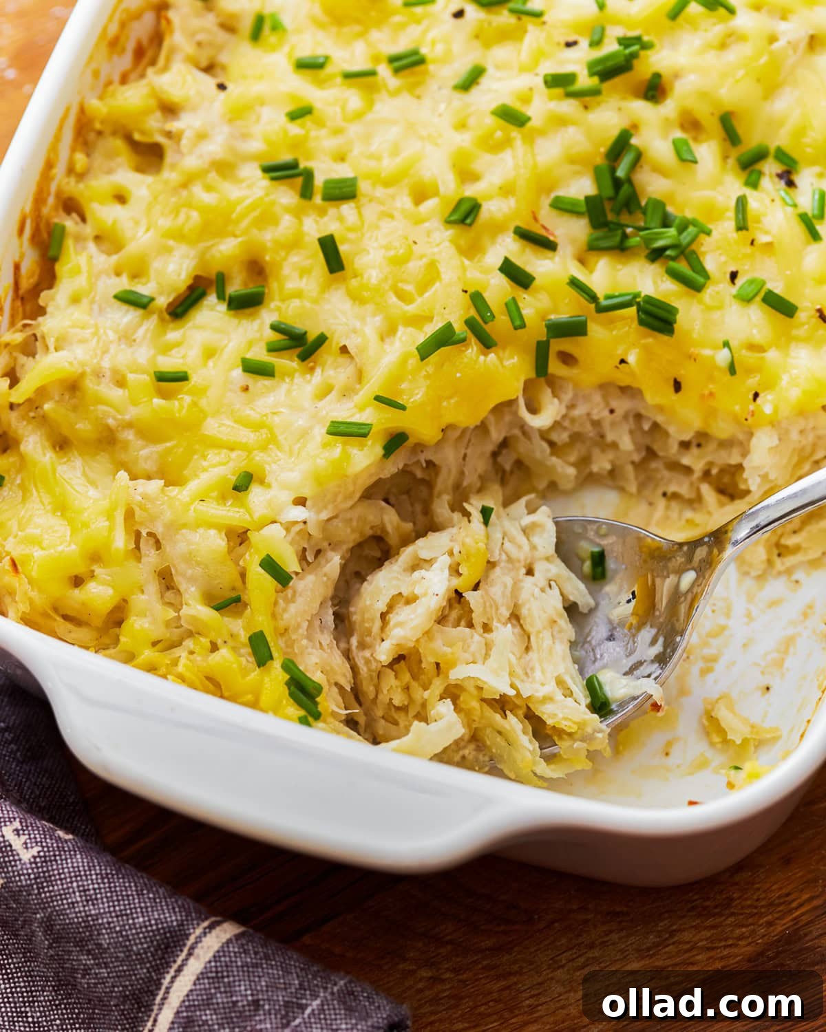 Overhead view of a spoon scooping out some dairy-free cheesy potatoes from a baking dish.