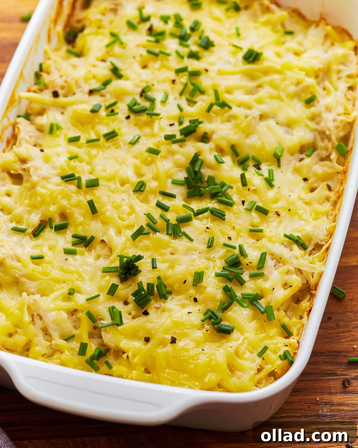 Overhead view of dairy-free cheesy potatoes in a baking dish, topped with fresh parsley.
