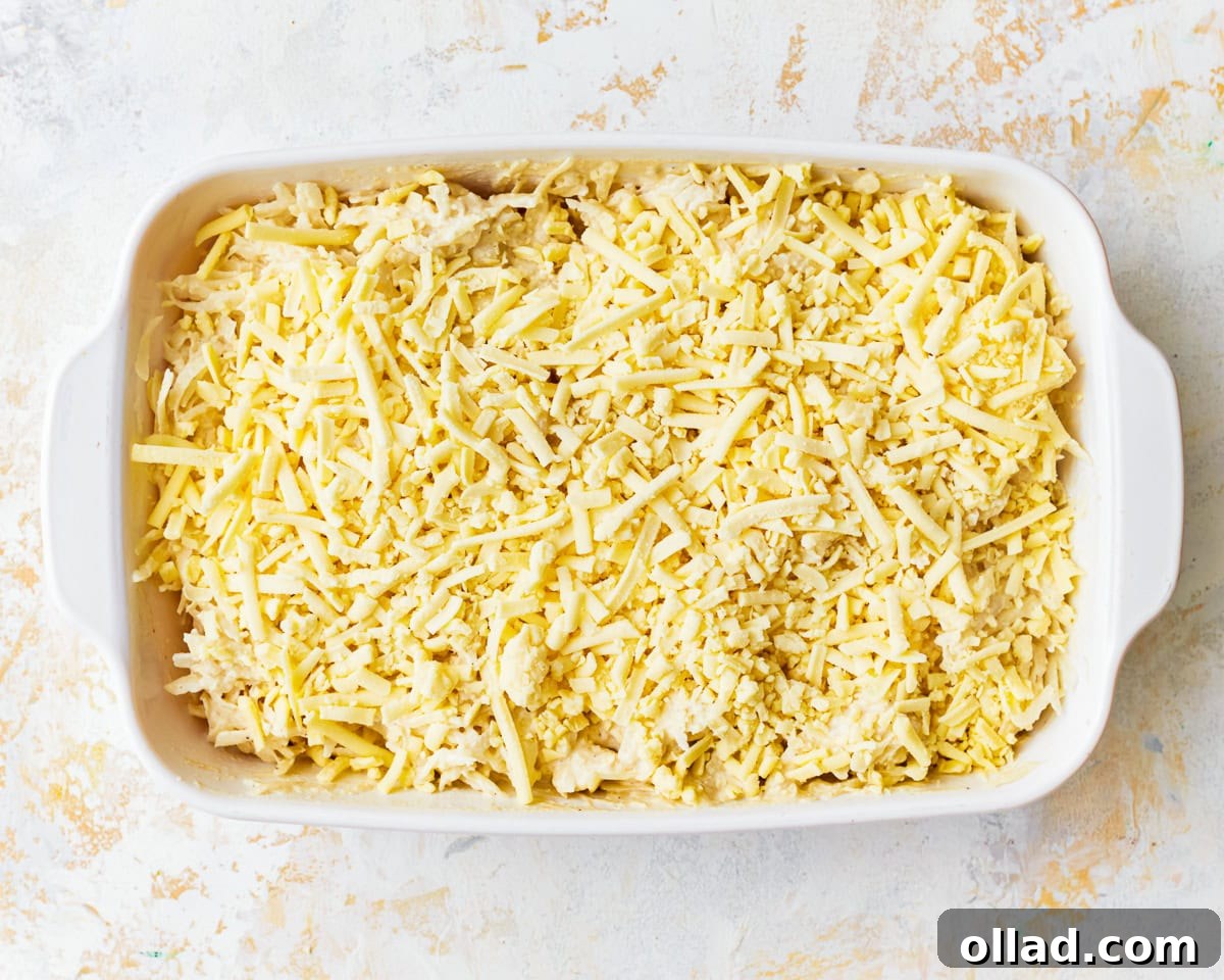 Grated potatoes in a baking dish covered in vegan cheese.