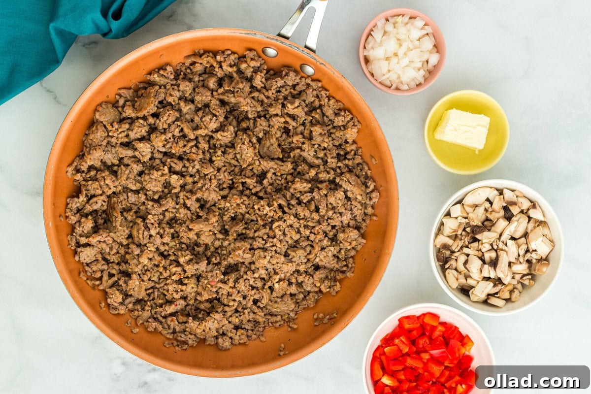overhead view of sausage cooking in orange skillet with other ingredients around