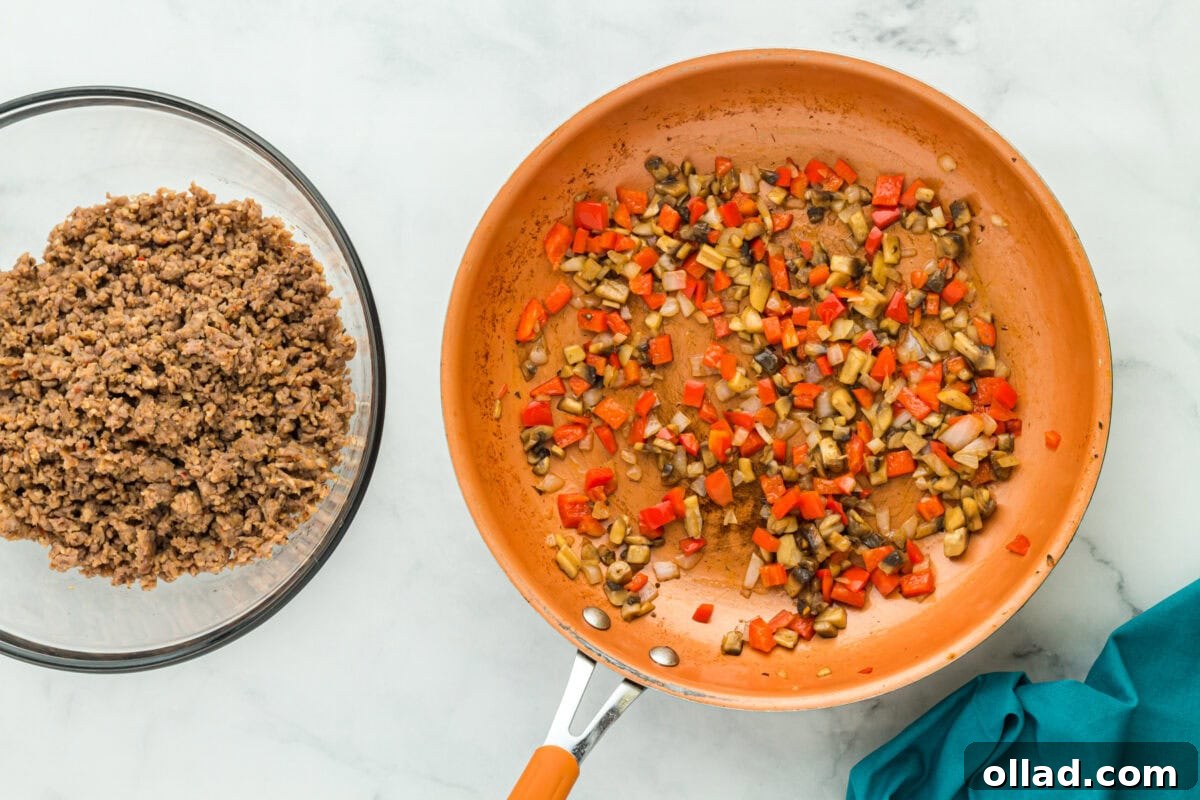 cooked sausage in a glass bowl next to orange skillet with red pepper and mushrooms cooking