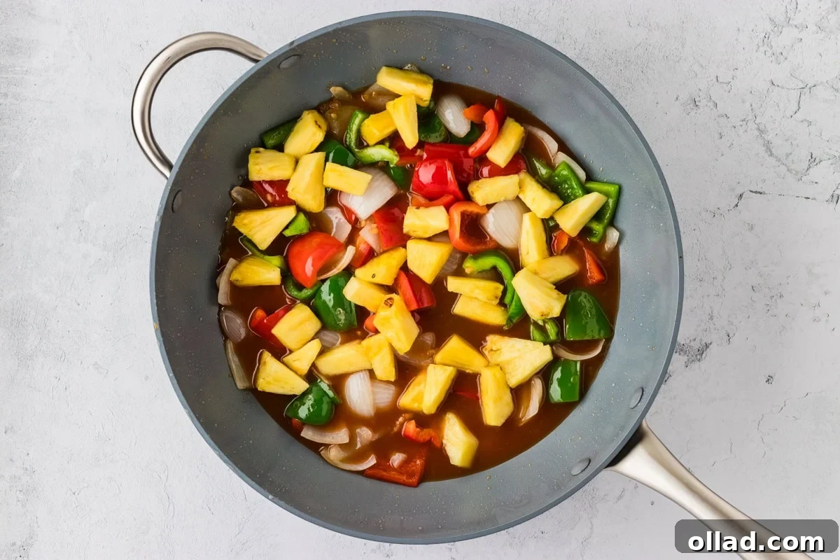 Irresistible Gluten-Free Sweet and Sour Chicken 17 overhead view of wok with stir fry veggies and pineapple chunks