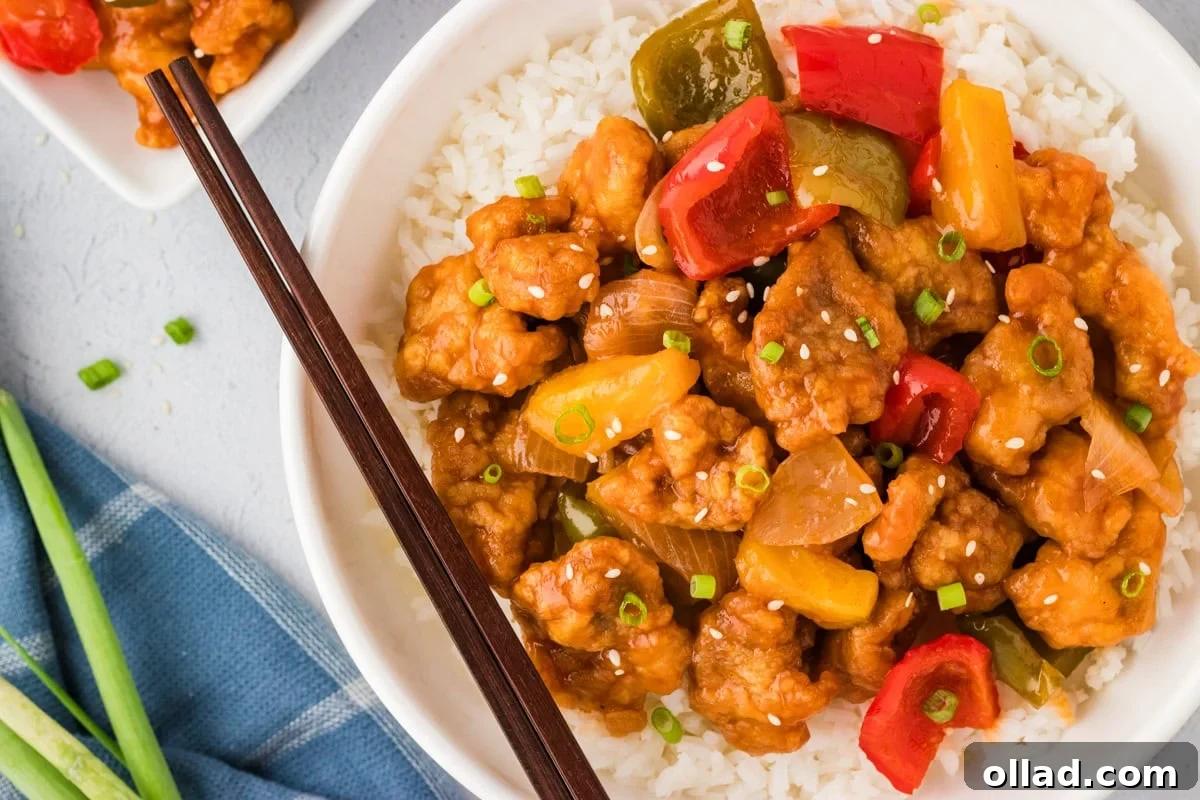 Irresistible Gluten-Free Sweet and Sour Chicken 19 overhead view of sweet and sour chicken with stir fry veggies over rice in white bowl with chopsticks
