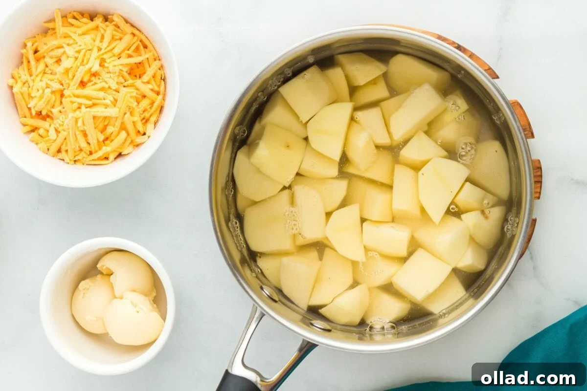 A large pot filled with water and uniformly cubed potatoes, boiling on a stovetop.