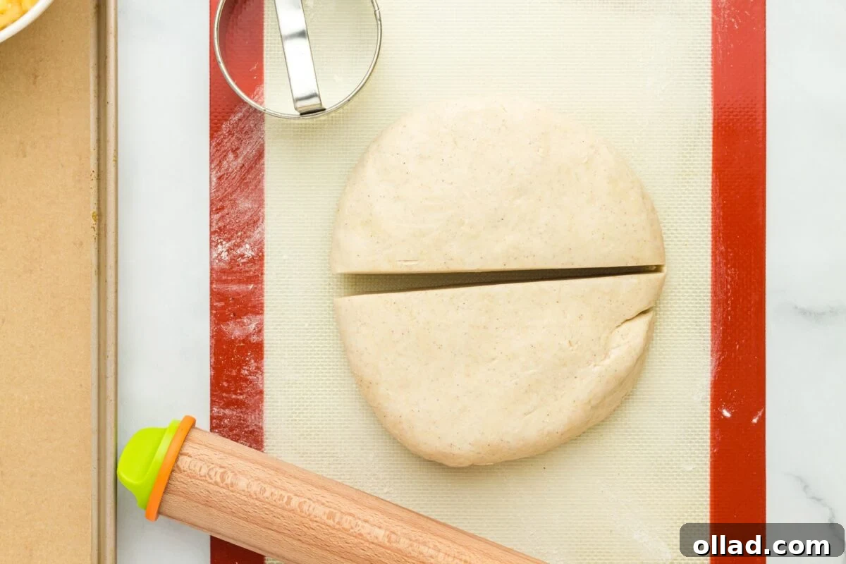 Pierogi dough, neatly cut in half, resting on a silicone mat dusted with flour, ready for rolling.