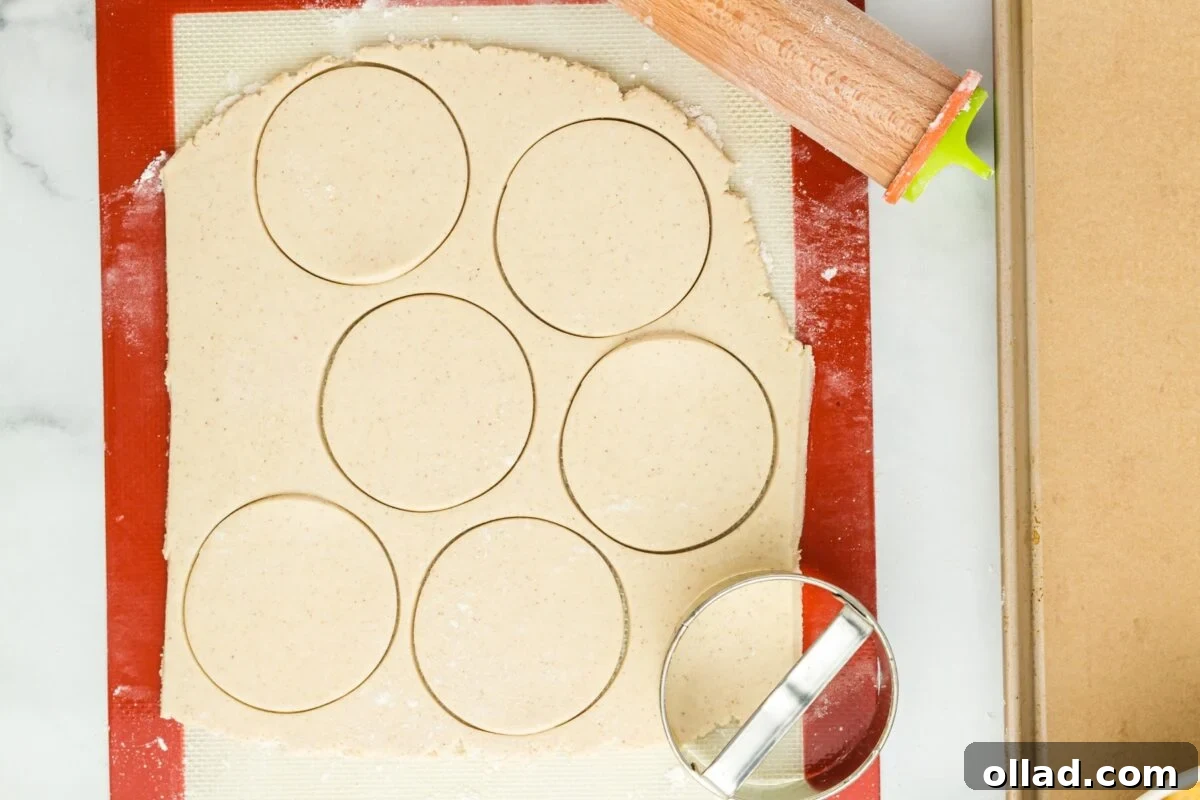 Six perfectly cut out circles of pierogi dough arranged on a floured surface, ready for filling.
