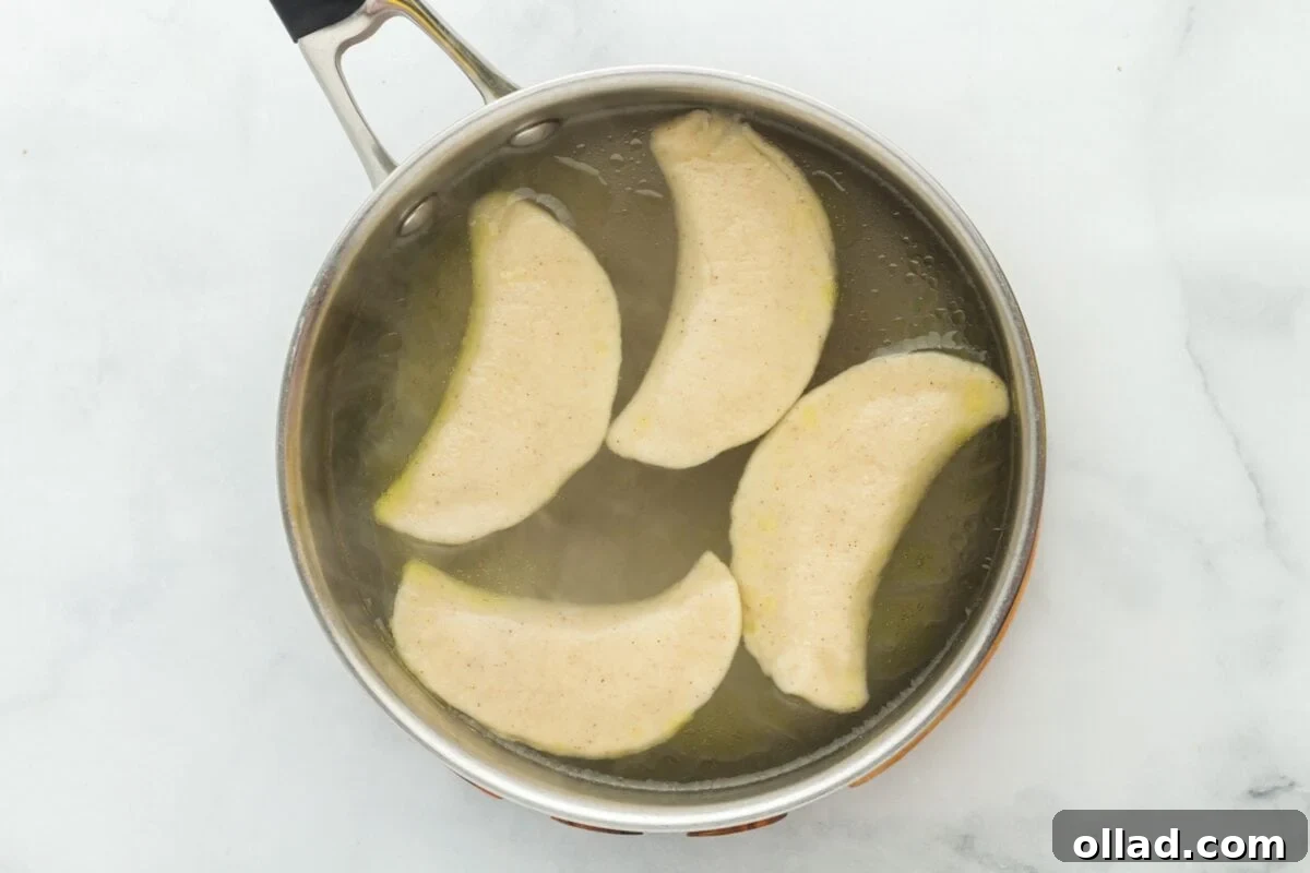 Delectable Gluten-Free Pierogi 20 Overhead view of four pierogi gently boiling and floating in a large pot of water.