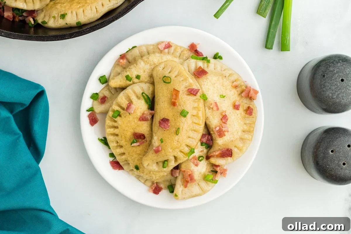 Delectable Gluten-Free Pierogi 7 Overhead view of a white plate generously topped with golden-brown gluten-free pierogi, garnished with fresh bacon and scallions, ready to be enjoyed.
