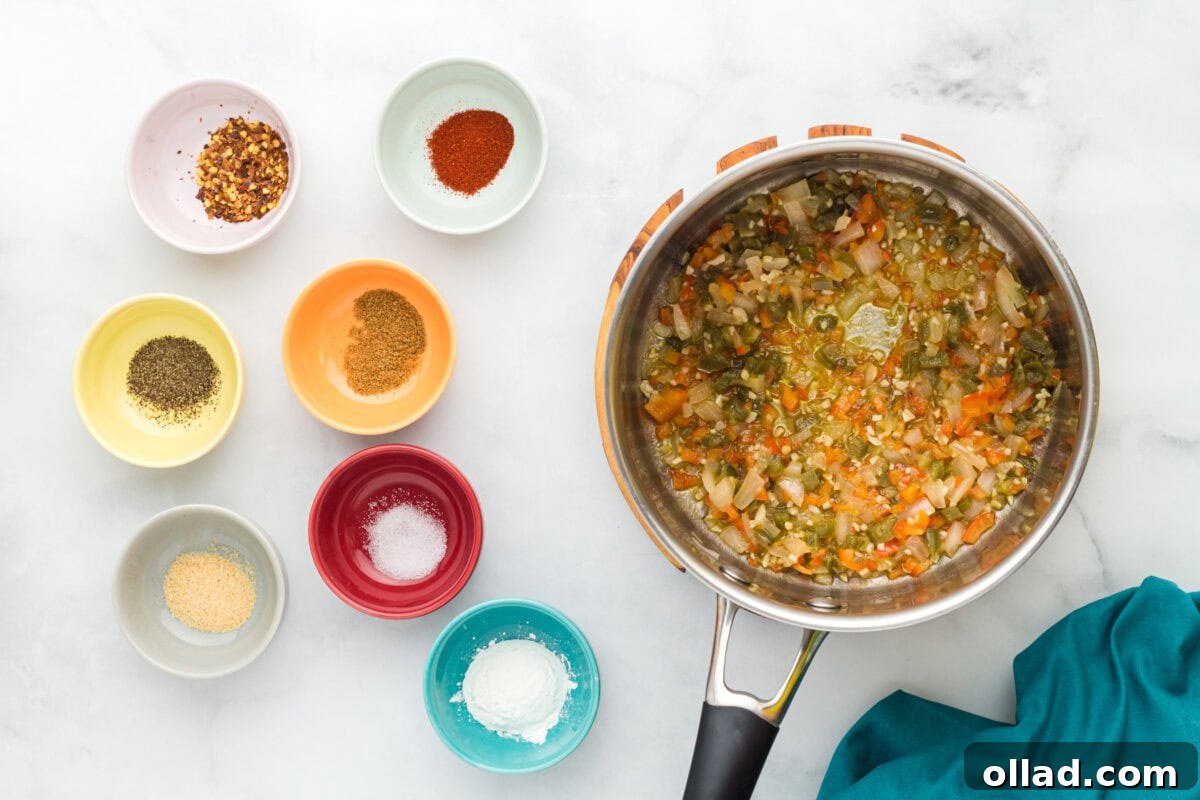 Diced onions, red bell pepper, jalapeños, and minced garlic gently sautéing in a stainless steel pot with vegan butter, creating the aromatic base for the queso.