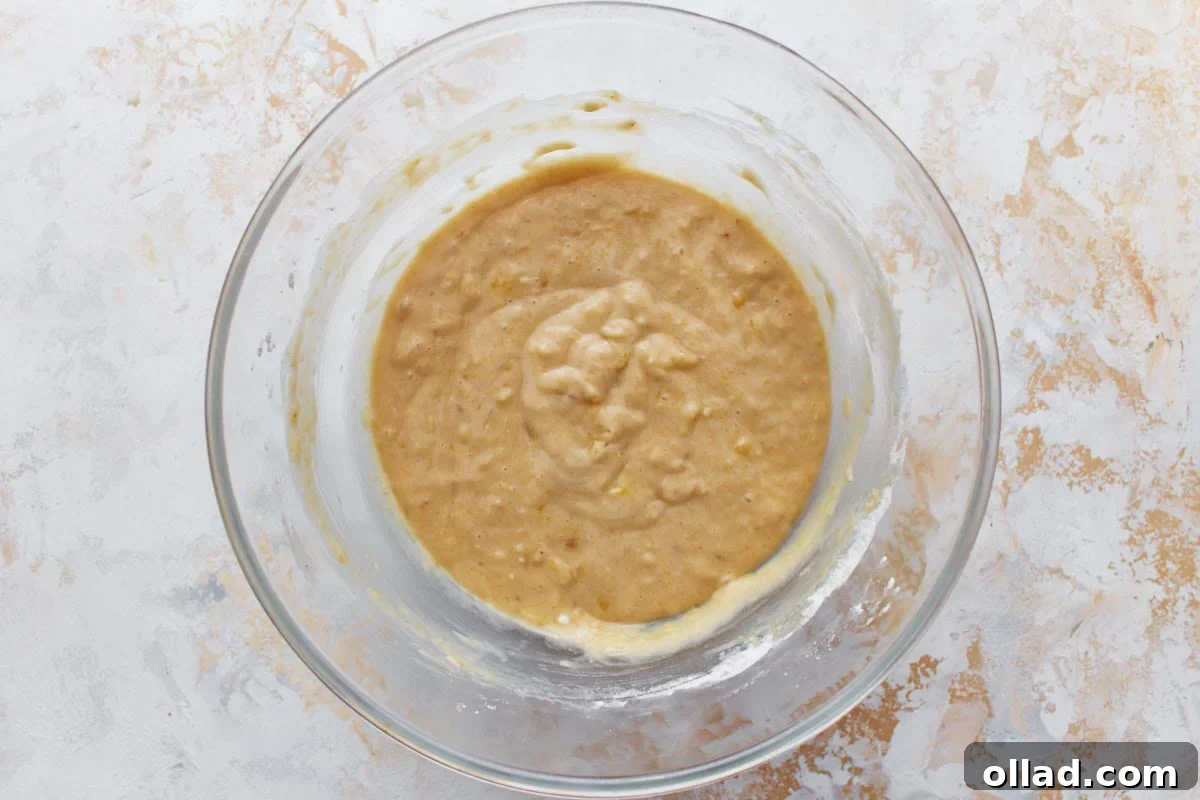 Irresistible Gluten-Free Banana Cake 6 A glass bowl filled with gluten-free banana cake batter, placed on a light, textured surface