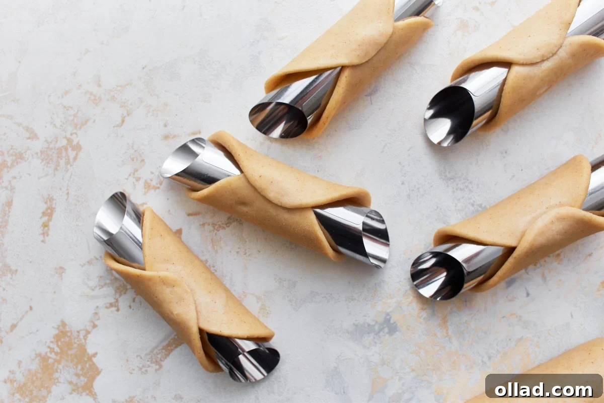 gluten-free cannoli dough formed on metal cannoli forms resting on a light colored surface