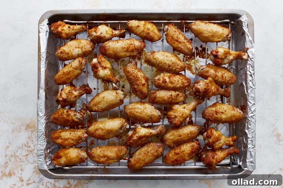 baked chicken wings coated in a dry rub lined up on a wire rack on top of a baking sheet