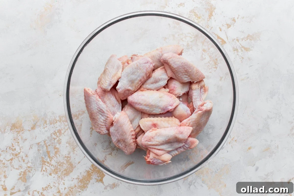 raw chicken wings in a glass bowl on a light colored surface