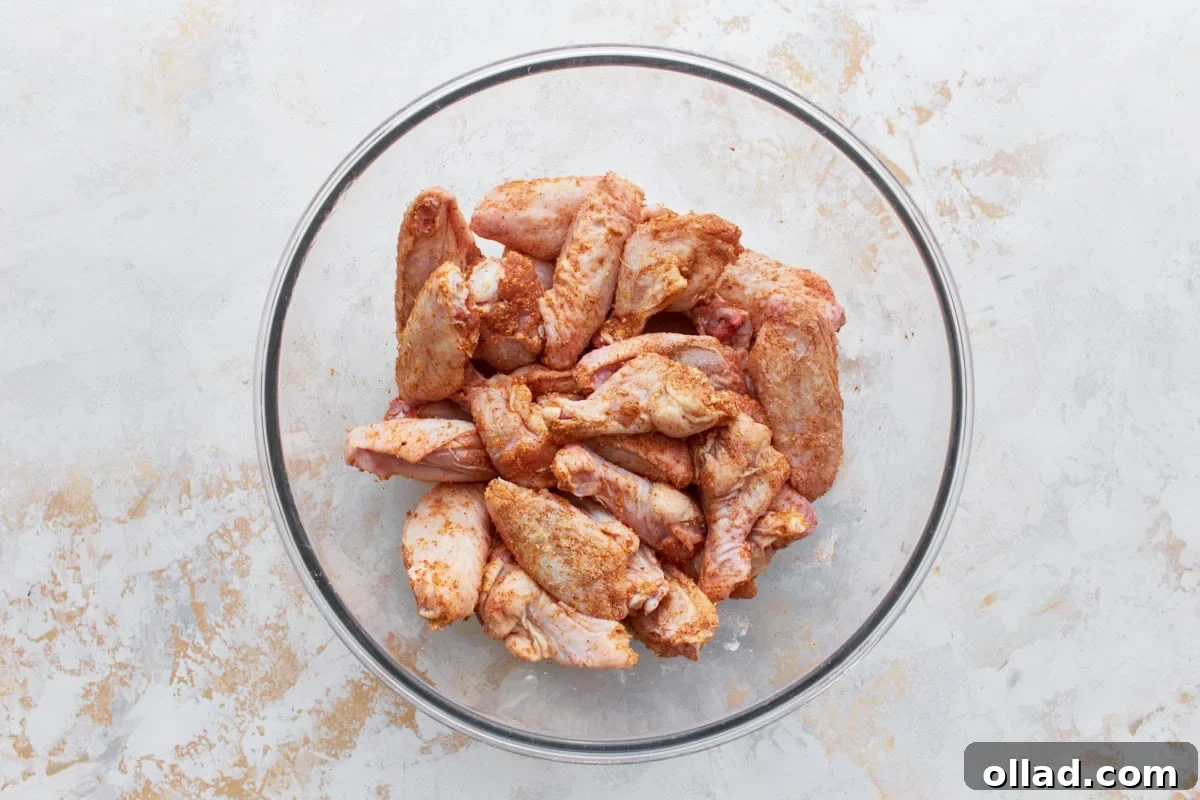 raw chicken wings coated in a dry rub in a glass bowl 