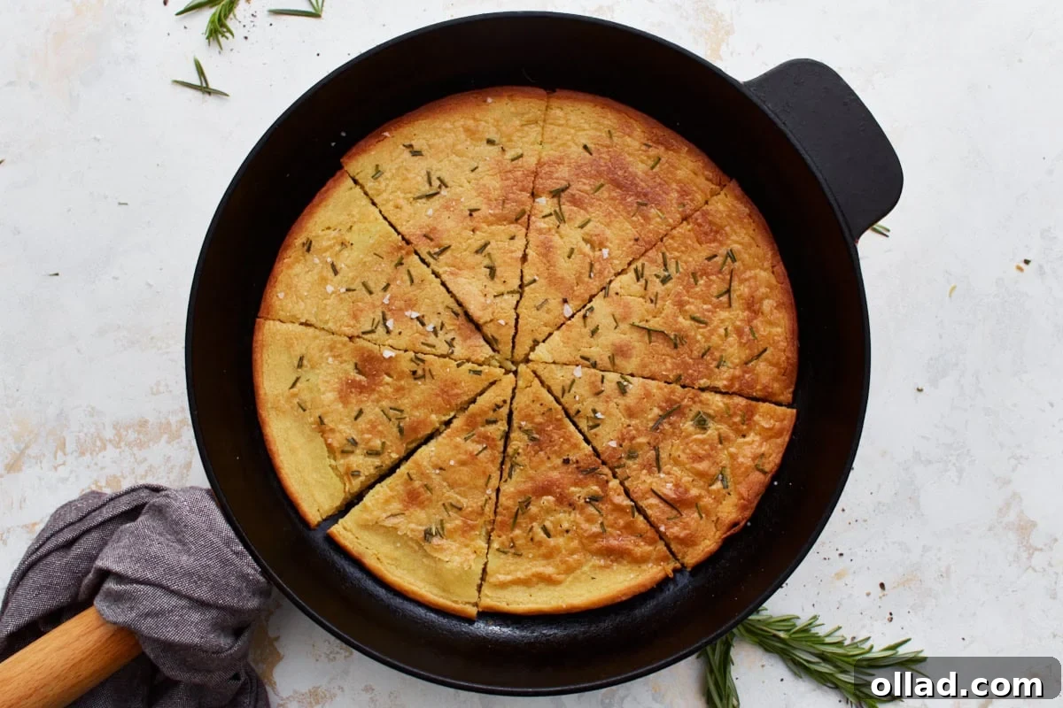 A cooked farinata in a cast iron skillet, perfectly sliced into wedges and adorned with fresh rosemary sprigs, ready to be enjoyed.