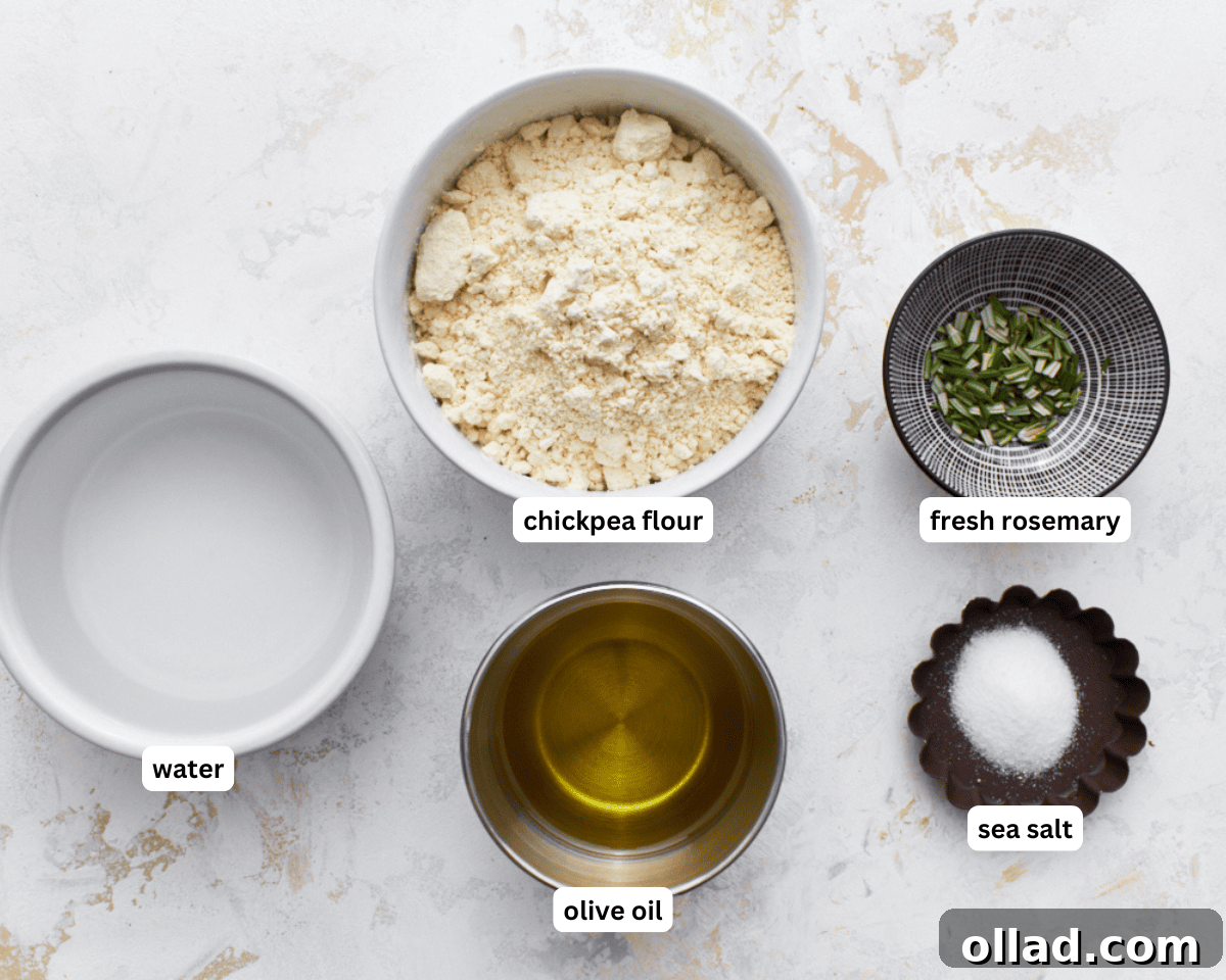 All the essential farinata ingredients laid out: chickpea flour, a bottle of extra virgin olive oil, fresh rosemary sprigs, and a bowl of sea salt.
