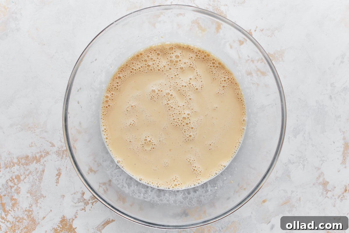 Egg and milk mixture in a glass mixing bowl resting on a light surface, ready to be combined.
