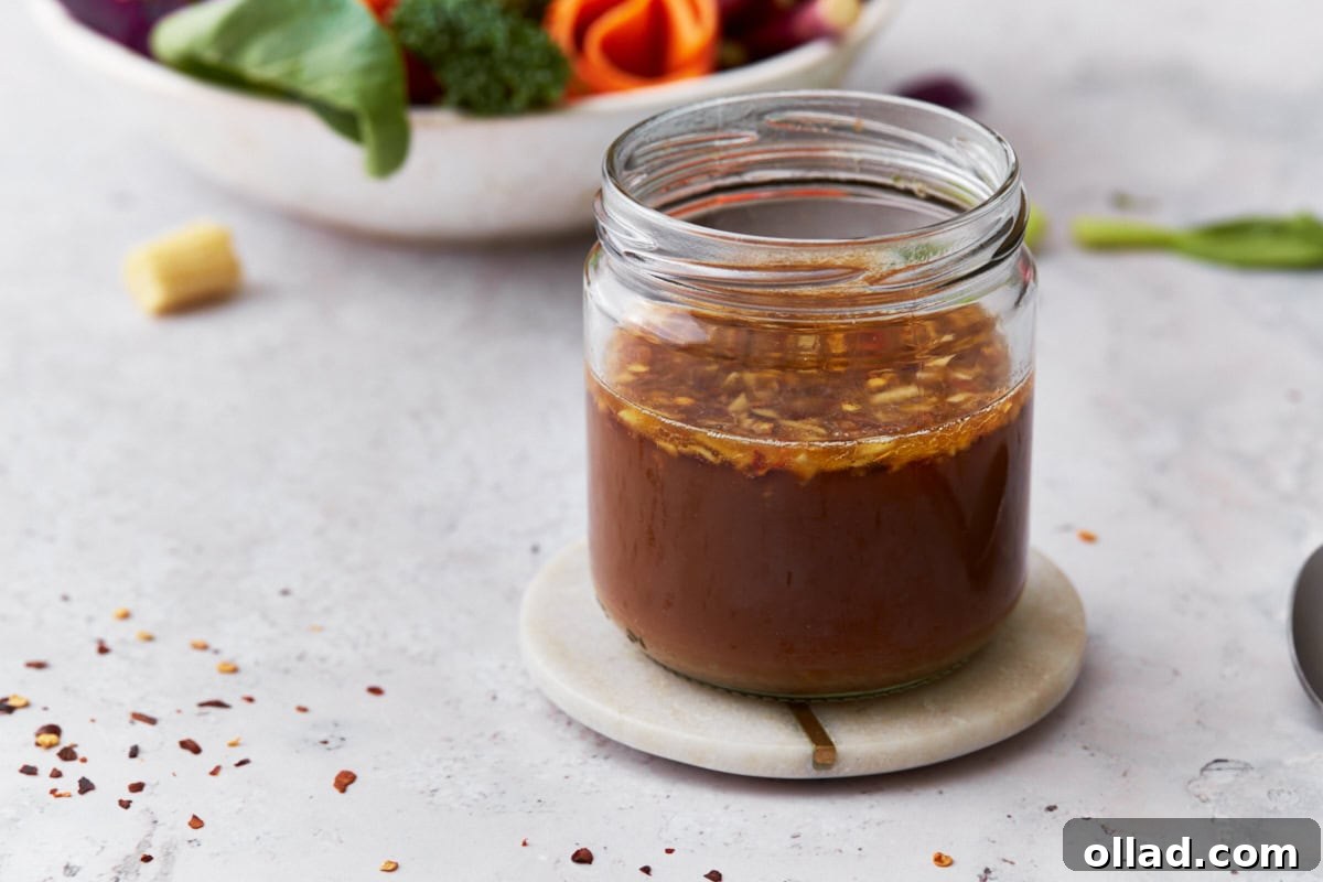 A jar of gluten-free stir-fry sauce placed on a white coaster, with a blurred bowl of fresh vegetables, including broccoli and carrots, in the background.