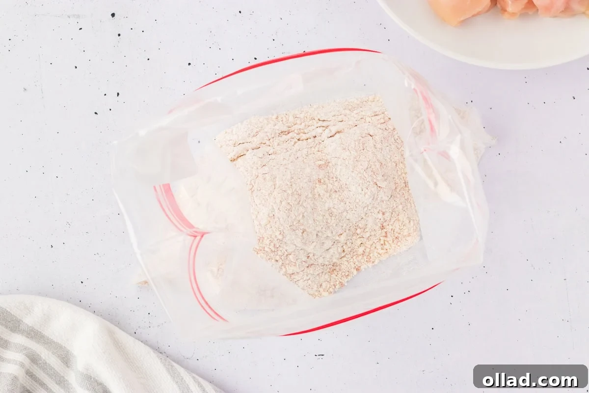 Overhead view of a zip-top plastic bag filled with a dry breading mix made from gluten-free Bisquick, Parmesan, and seasonings.
