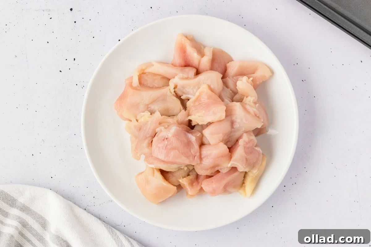 Plate of raw, diced chicken breast cut into nugget-sized pieces, ready for coating.