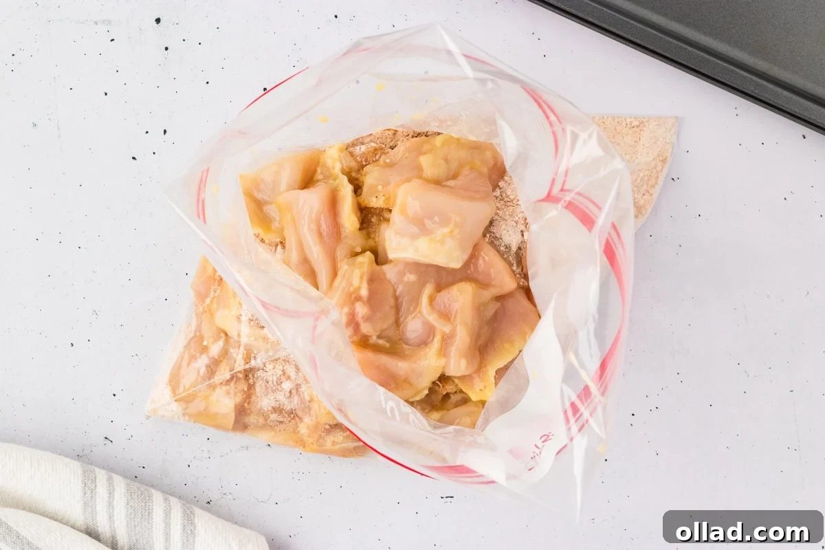 Raw chicken pieces added to the bag of seasoned flour mix, ready to be coated.