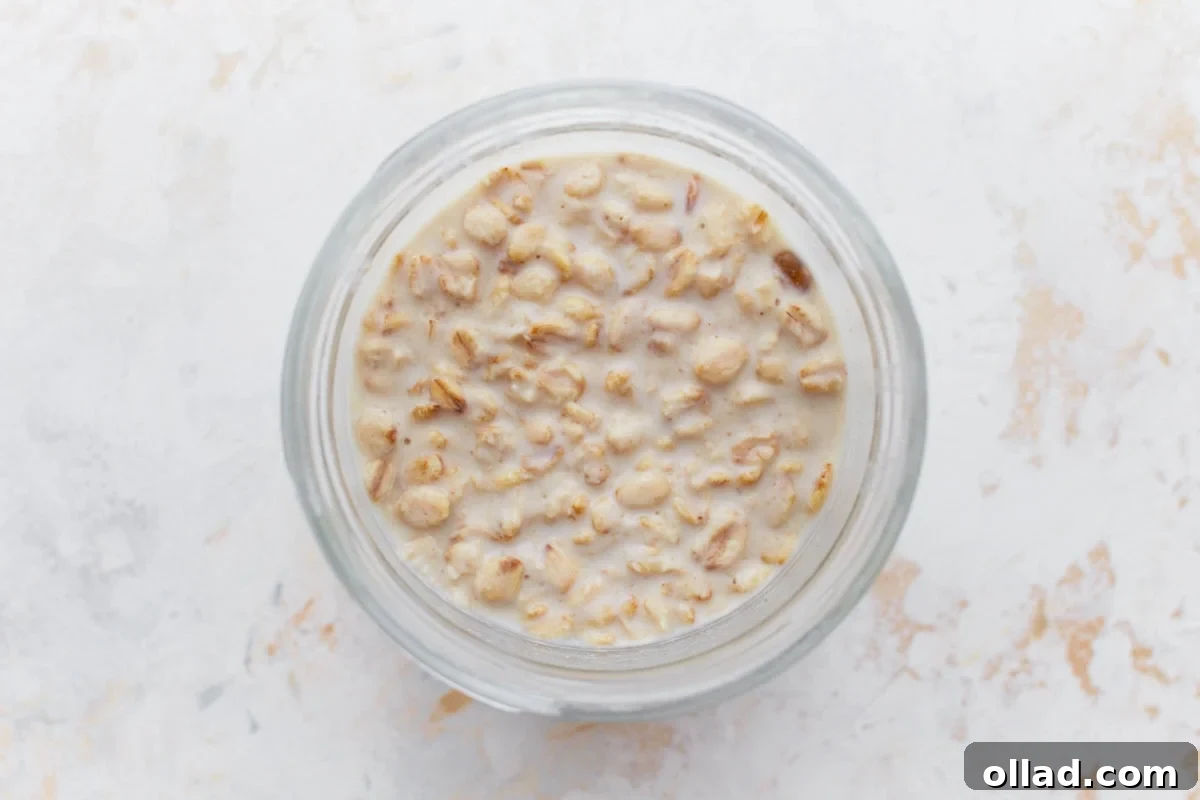 A close-up of gluten-free overnight oats in a glass jar after being soaked, showing a creamy and slightly thickened texture.